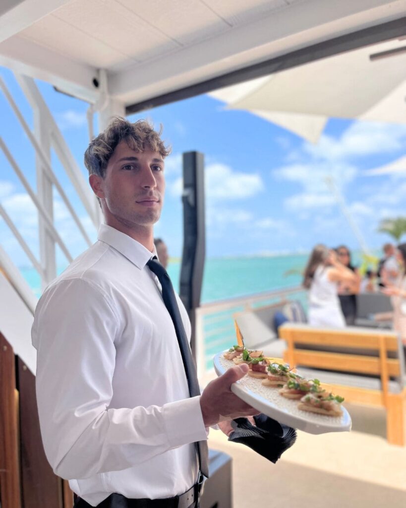 Elegant UCD server carrying canapé tray aboard luxury yacht