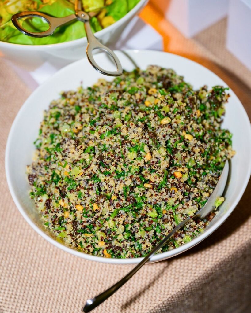 A fresh bowl of quinoa salad with herbs, vegetables, and grains served in a white dish.