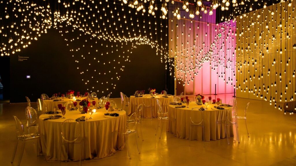 Corporate dinner setup at Superblue Miami under hanging bulb installation