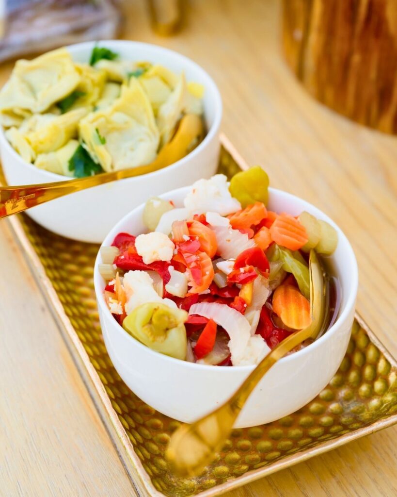 Colorful gourmet antipasti bowls with pickled vegetables and marinated artichokes at a Miami garden wedding.