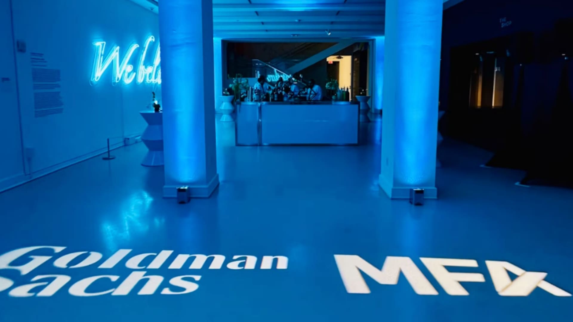 Blue-lit entrance of The Bass with Goldman Sachs branding on the floor