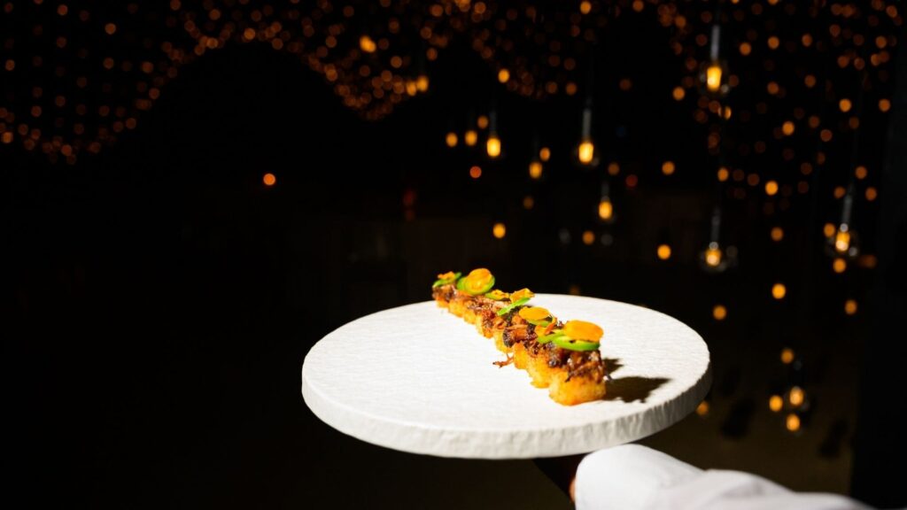 Elegant canapé plated on a minimalist white dish under hanging lights