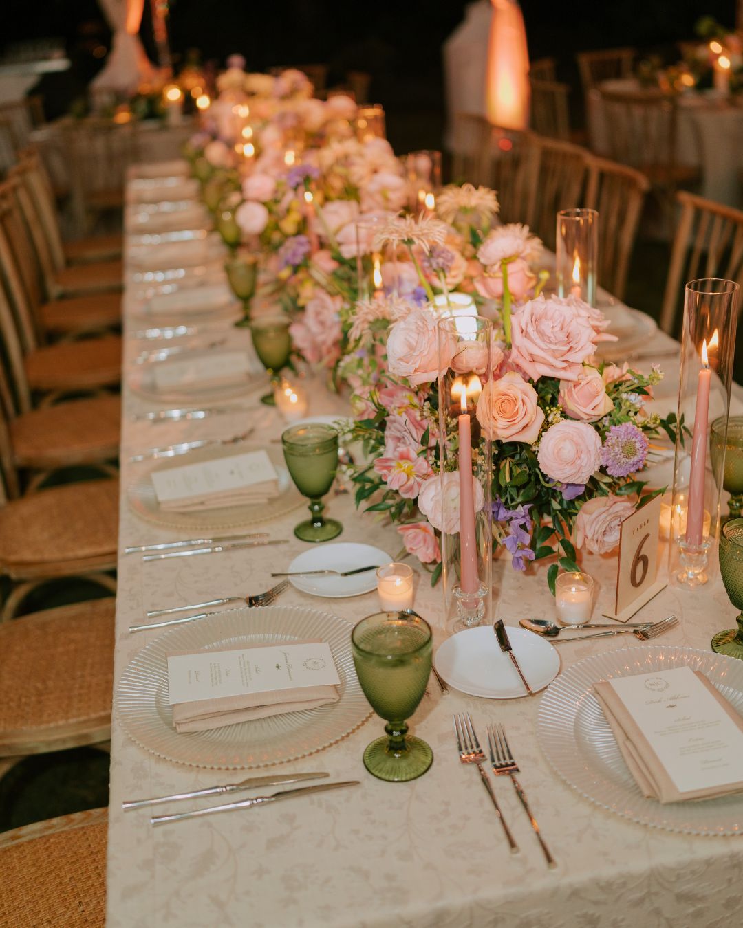 Elegant wedding reception table with floral centerpiece, candles, and fine dining setup.