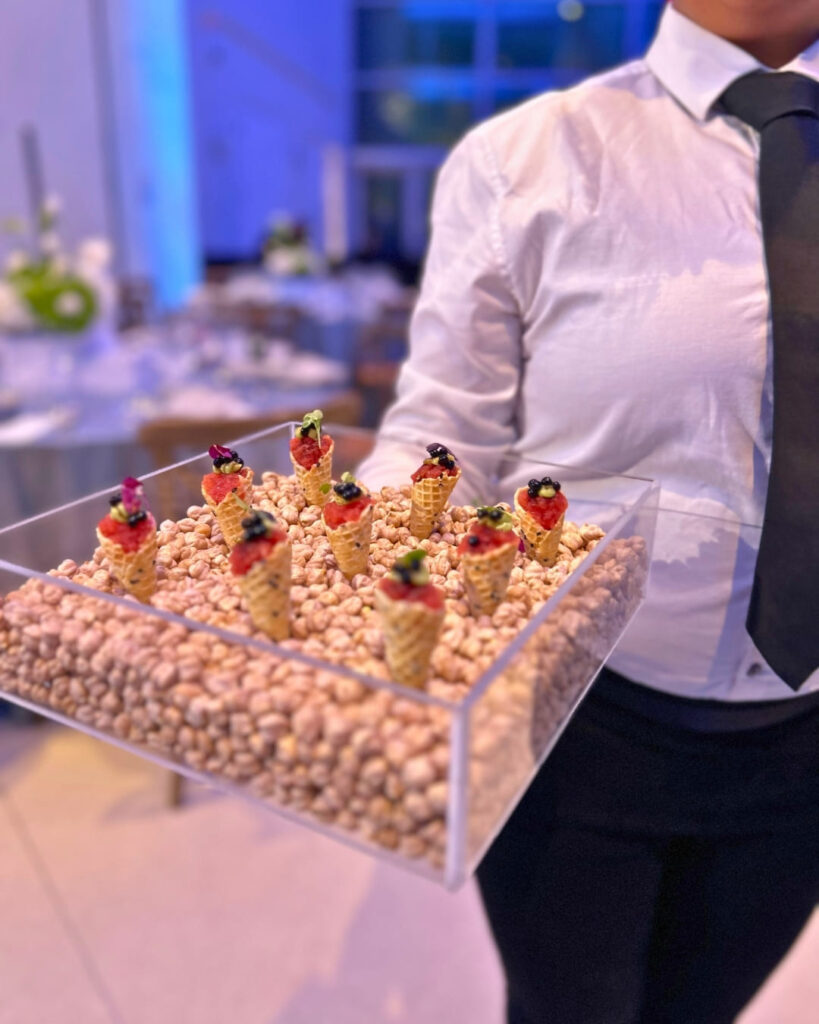 Server offering miniature tuna tartare cones over a bed of chickpeas