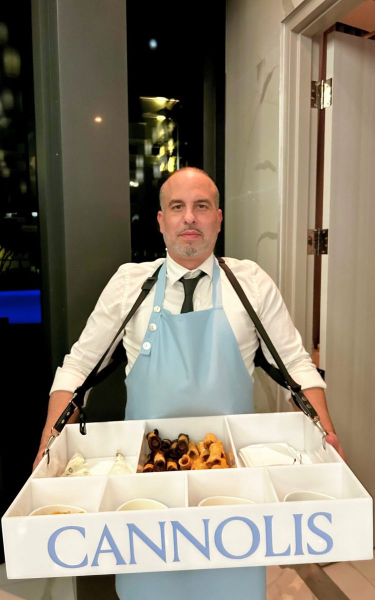 Server offering wearable tray of fresh cannolis and fillings.