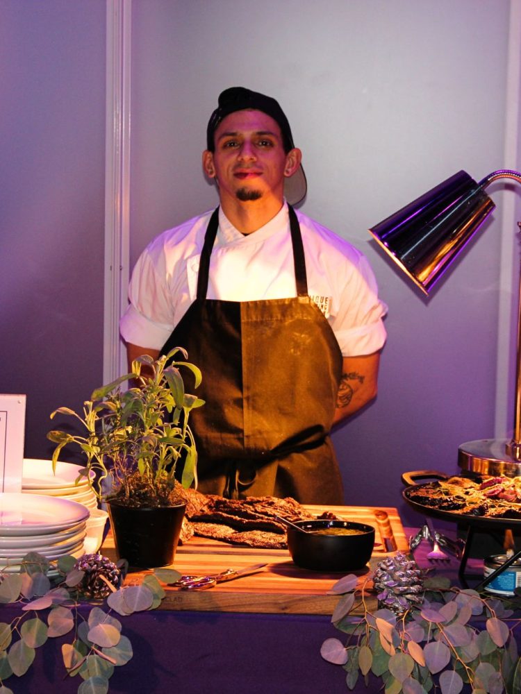 Chef at catering station serving grilled meats at an elegant event.