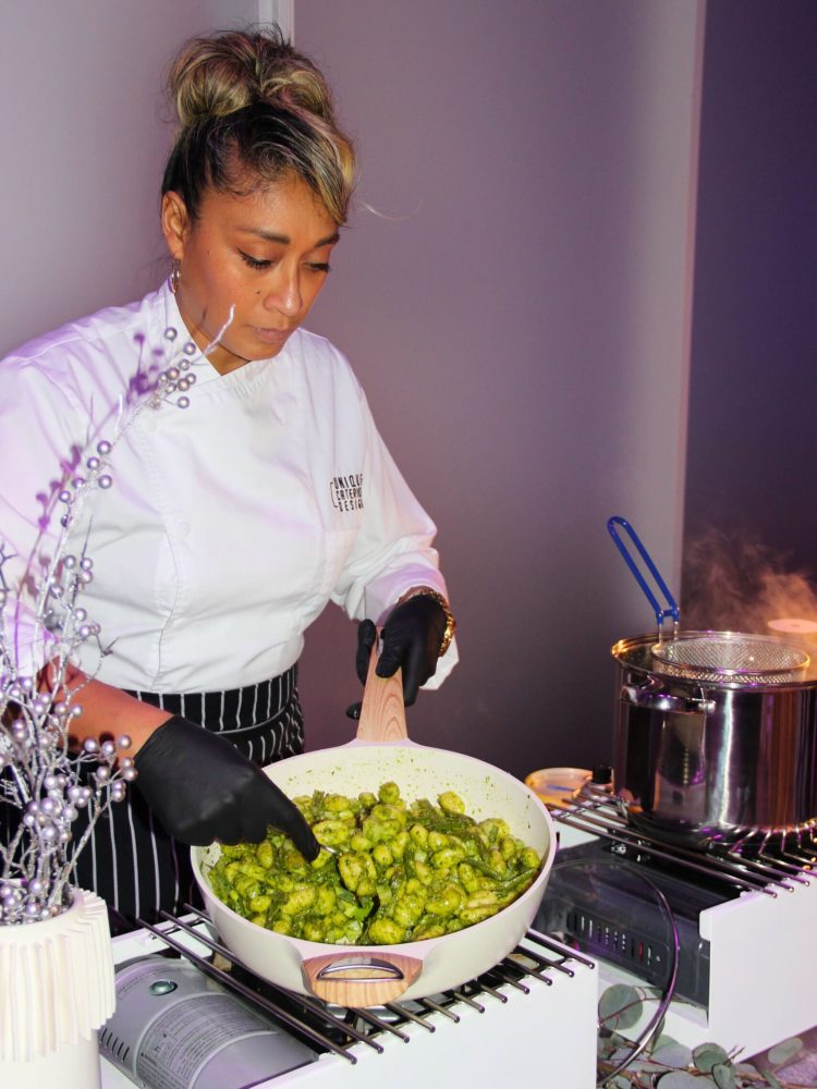 Chef sautéing pesto gnocchi at a live cooking station.