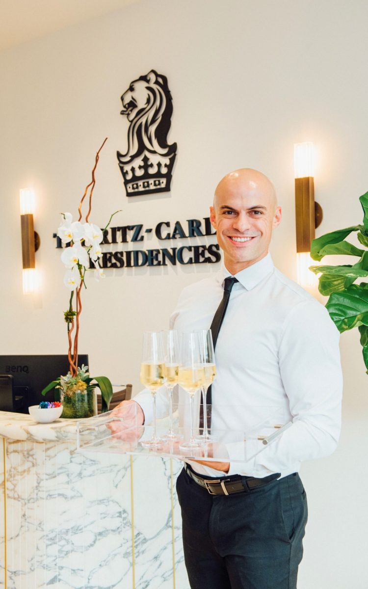Smiling server holding champagne flutes at The Ritz-Carlton Residences.