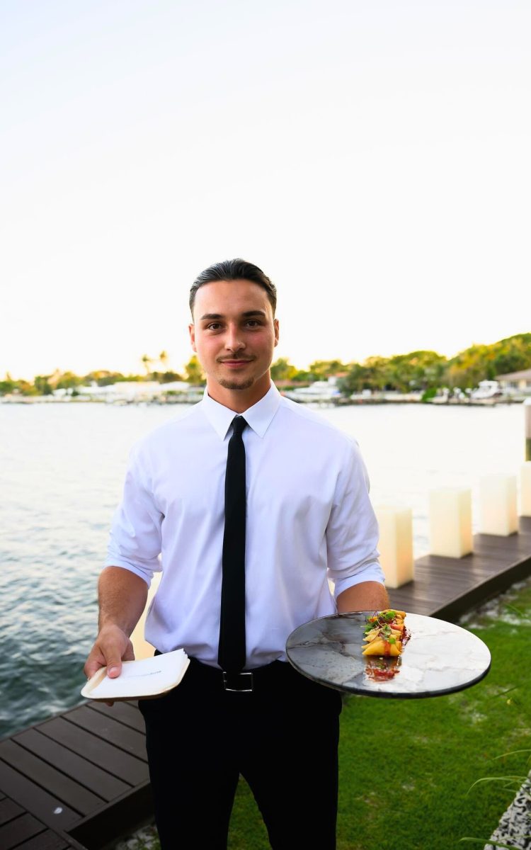 Server showcasing refined canapé at a waterfront event.