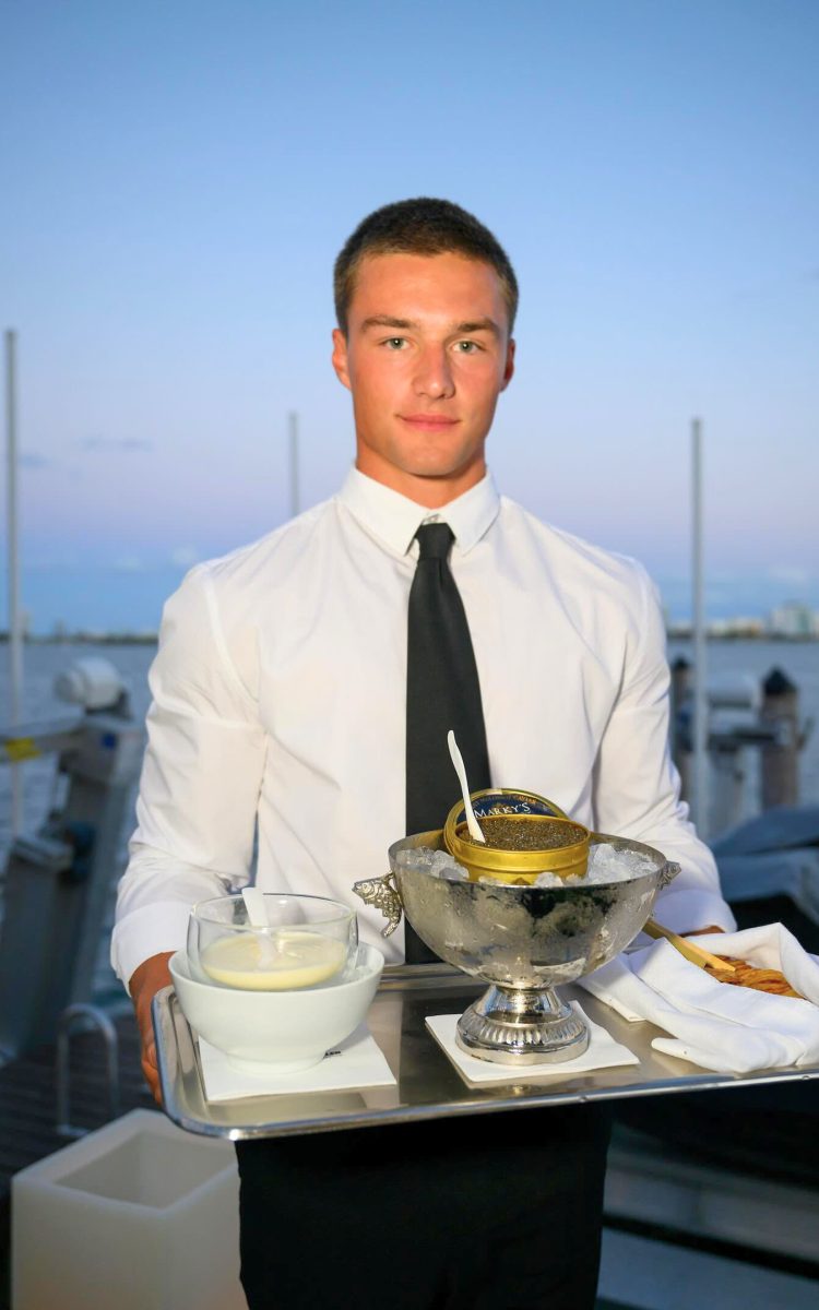 Server standing dockside presenting an upscale caviar service tray.