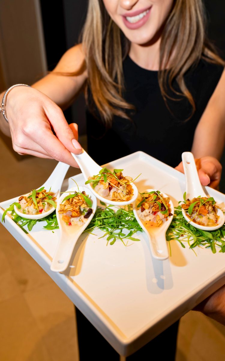 Woman presenting gourmet hors d’oeuvres in ceramic tasting spoons.